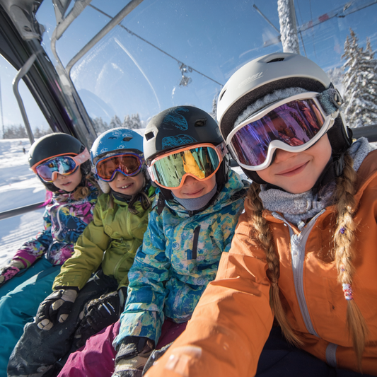 Children wearing ski gear on a ski lift with snowy landscape and blue sky in the background.